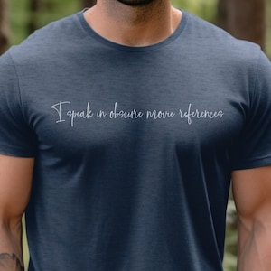 May include: A navy blue t-shirt with the text "I speak in obscure movie references" printed in white on the front.