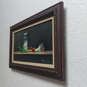 K&ouml;nnte beinhalten: Gerahmtes Stillleben-Gem&auml;lde mit einem Salzstreuer, Fr&uuml;hlingszwiebeln, roten Paprika und einer Knoblauchzehe. Das Kunstwerk ist vor einem dunklen Hintergrund mit einem Holztisch platziert. Der Rahmen ist dunkelbraun mit goldenen Akzenten.