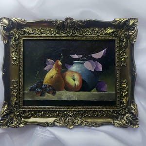 Peut inclure: Une peinture de nature morte dans un cadre doré représente une poire, une pomme et un vase bleu avec des feuilles violettes sur un fond sombre.