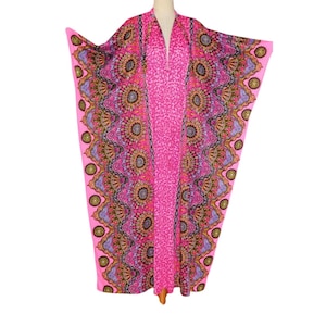 May include: A floor-length kaftan featuring a vibrant pink base with a central panel of small pink patterns. The garment is adorned with wide side panels displaying a repeating circular mandala-style print in shades of purple, gold, and black.