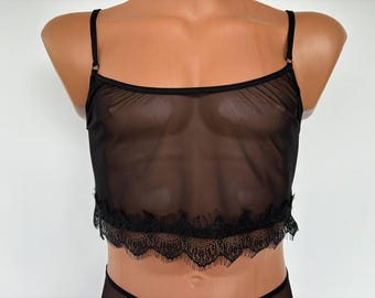May include: Black sheer mesh top with a lace trim. The top has thin straps and a scoop neck.