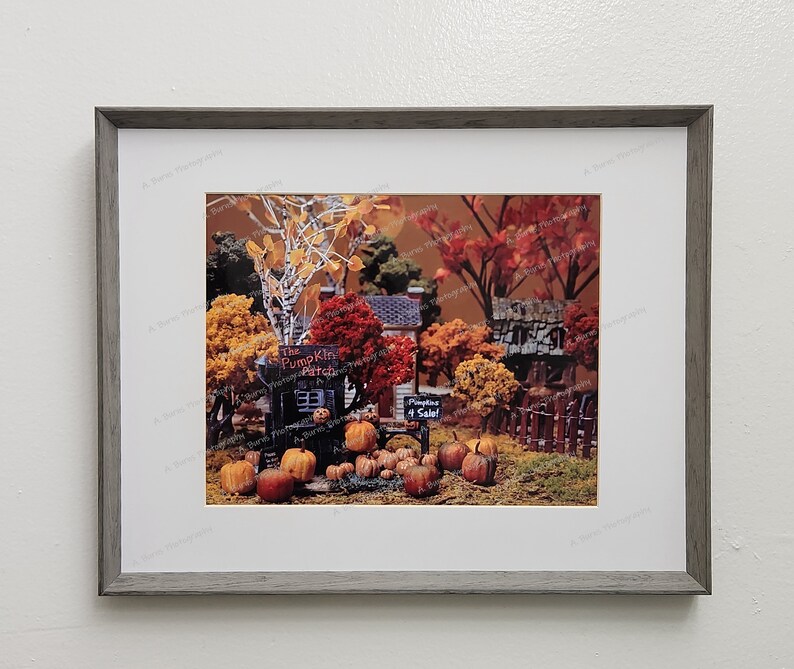 Puede incluir: Una escena de oto&ntilde;o en miniatura con un peque&ntilde;o edificio de madera con la etiqueta "The Pumpkin Patch". Hay calabazas, hojas de oto&ntilde;o y un cartel que dice "Pumpkins 4 Sale!"