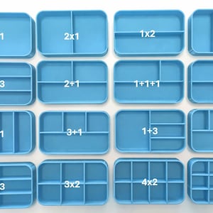 Puede incluir: Una colección de dieciséis organizadores de plástico azul claro con varias configuraciones de compartimentos, etiquetados con números como "1x1", "2x1" y "4x3". Diseñados para almacenamiento y organización.