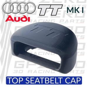 Puede incluir: Una tapa superior de cinturón de seguridad gris oscuro con el logotipo de Audi TT MKI. La tapa tiene forma curva y rectangular, con el texto "TOP SEATBELT CAP" en un rectángulo azul en la parte inferior. El logotipo de Audi está en la parte superior izquierda.