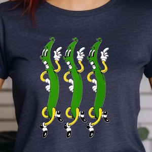 May include: A navy blue t-shirt with a graphic of four green beans with faces and arms, wearing yellow shoes and black socks. The beans are arranged in a line, with their arms raised and their faces looking to the right.