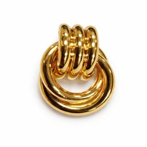 May include: A polished gold-tone metal earring featuring a circular hoop design with three interconnected, smooth, rounded loops that overlap to create a layered, dimensional appearance with a high-shine reflective surface finish.