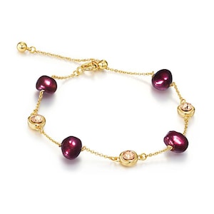 Puede incluir: Pulsera dorada con un diseño de cadena fina. Cuenta con perlas de color burdeos oscuro y pequeñas piedras preciosas redondas de color melocotón engastadas en biseles dorados. El cierre es ajustable.