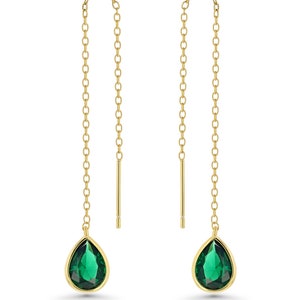 Peut inclure: Une paire de boucles d'oreilles pendantes dorées avec des cristaux verts en forme de goutte.