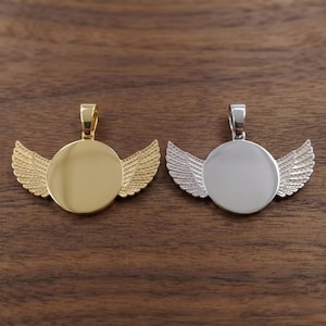 May include: Two circular pendants with attached wings on each side. One pendant is polished gold-tone metal, and the other is polished silver-tone metal. Each piece features a smooth, round center and a small bail at the top for hanging.