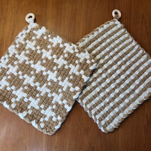 May include: Two brown and white woven pot holders with wooden rings. The pot holders have a checkered pattern.