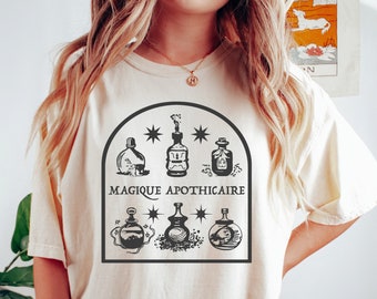 May include: A white t-shirt with a black graphic of five potion bottles and the text "Magique Apothecaire".