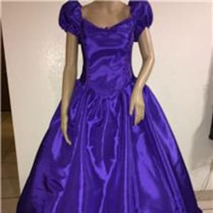 May include: A vibrant purple ball gown with a sweetheart neckline and short, puffed sleeves. The dress features a full skirt with ruffled trim at the hem. The satin fabric has a glossy sheen, and the dress is displayed on a mannequin.
