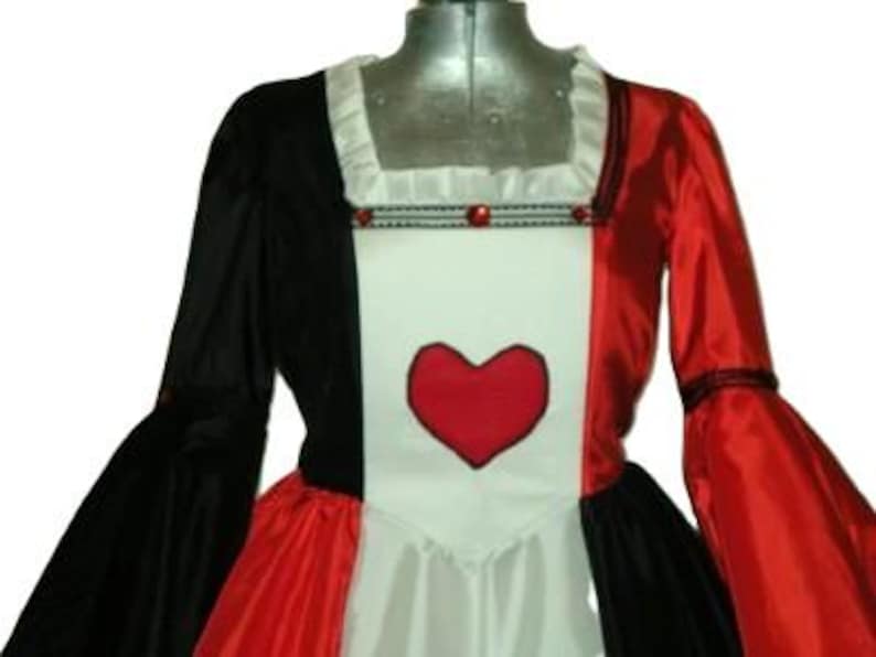 May include: A dress featuring a color-blocked design with a black right side and a red left side. The center panel is white and displays a large red heart appliqu&eacute;. The neckline is square with white ruffles and a trim accented by red beads.