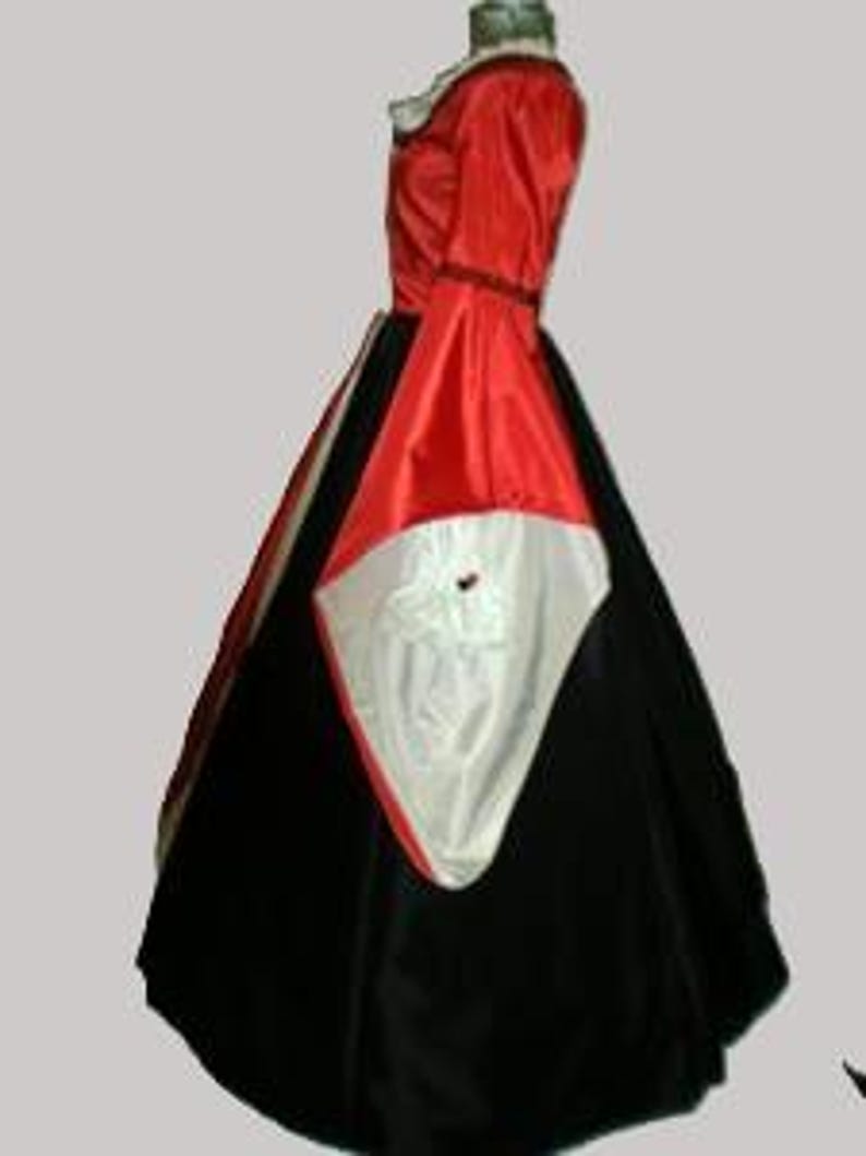 May include: A floor-length gown featuring a vibrant red bodice with long, wide sleeves that reveal a white lining. The skirt is constructed from a combination of black fabric panels and a prominent white triangular insert at the front center.