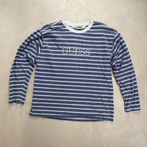 Peut inclure: Un t-shirt à manches longues rayé bleu et blanc avec le mot "GUESS" brodé sur le devant.