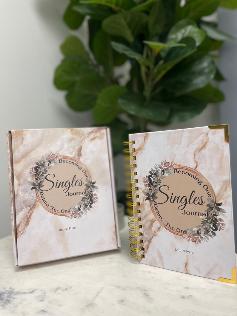 May include: A journal and matching box set with a marble design. The journal and box feature the text "Becoming One Singles Journal Before 'The One'" in a circular design with floral accents. The author's name, Brittnei Price, is also printed on the journal and box.