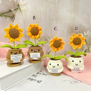 May include: Four crocheted sunflower plants in brown and white pots with inspirational messages. The messages are "Emotional Support Plant Life can be tough sometimes, but remember so are you!" and "In a world full of roses, be a sunflower."