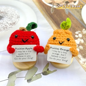 Puede incluir: Dos juguetes de peluche de crochet con forma de manzana y naranja, cada uno sosteniendo un cartel con un mensaje positivo. La manzana es roja y la naranja es naranja. Los carteles dicen "Manzana Positiva Puede que sea una manzana pequeña, pero creo en ti. ¡Haz lo que tengas que hacer!" y "Naranja Positiva Puede que sea una naranja pequeña, pero creo en ti. ¡Haz lo que tengas que hacer!"