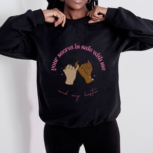 May include: Black sweatshirt with a pink graphic that says "Your secret is safe with me and my bestie". The graphic features two hands holding pinky fingers together.