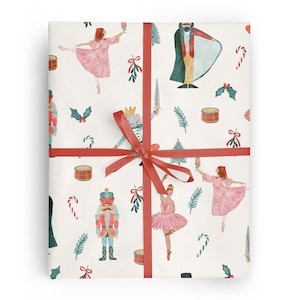 May include: White wrapping paper with a red ribbon. The paper features a repeating pattern of illustrations of characters from the Nutcracker ballet, including a ballerina, a nutcracker soldier, a mouse king, and candy canes.
