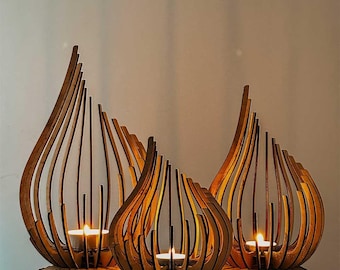 May include: Three brown wooden candle holders with a vertical, curved, slat-like design. Each holder features a hollow center containing a small, lit tea light candle. The structures are arranged in a cluster, creating a warm, glowing effect.