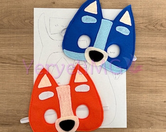May include: Two felt animal masks, one blue and one orange, with white accents. The masks have black eyes and noses and are designed to look like dogs.