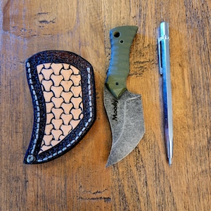 May include: A small, green and black pocket knife with a curved blade and a leather sheath. The knife has the word "Moody" engraved on the handle.