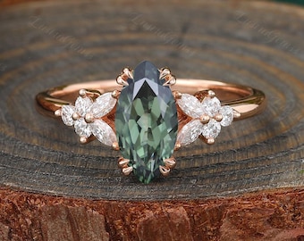 May include: A marquise cut green gemstone engagement ring set in rose gold with a floral design featuring smaller diamonds.