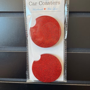 May include: Two red glitter car coasters in a clear plastic packaging. The packaging has a white label that says "Car Coasters" and "Handmade with Love".