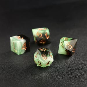 Op de afbeelding: Vier polyhedrale dobbelstenen met een groen en zwart marmer effect. De dobbelstenen hebben koperkleurige cijfers en randen. De set bevat een D4, D6, D8 en D20, perfect voor tabletop games.