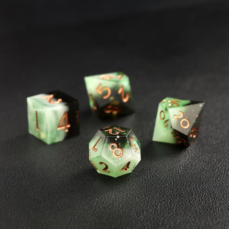 Op de afbeelding: Vier polyhedrale dobbelstenen met een groen en zwart marmer effect. De dobbelstenen hebben koperkleurige cijfers en randen. De set bevat een D4, D6, D8 en D20, perfect voor tabletop games.