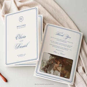 Pode incluir: Cartões de convite de casamento com borda azul marinho e texto. A frente do cartão diz "Bem-vindos ao nosso casamento" com os nomes Olivia e Daniel. O interior apresenta uma foto e as palavras "Obrigado".