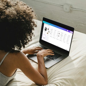 May include: A person using a laptop computer to design wedding templates. The screen shows a variety of wedding-related designs, including a wedding invitation, a seating chart, and a thank you card.