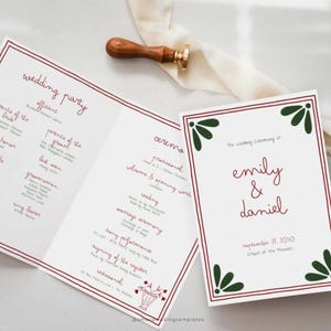 Könnte beinhalten: Hochzeitsprogramme mit roten und grünen Akzenten. Die Programme zeigen die Namen "Emily & Daniel" und das Datum "27. September 2050". Ein Wachssiegel mit Holzgriff liegt auf einem weißen Band.