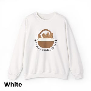 Peut inclure: Sweat-shirt blanc avec un motif de panier &agrave; pain et le texte "in my sourdough era" dans un design circulaire. Le sweat-shirt est de style col rond.