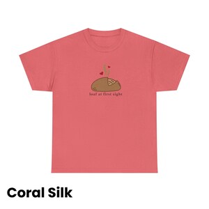 Puede incluir: Camiseta de seda color coral con un gr&aacute;fico de una hogaza de pan con vapor y corazones, y el texto "loaf at first sight". La camiseta es de color coral liso.