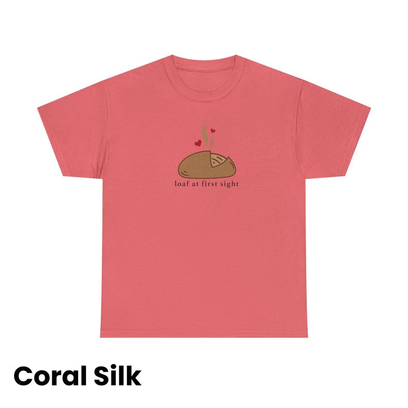 Puede incluir: Camiseta de seda color coral con un gr&aacute;fico de una hogaza de pan con vapor y corazones, y el texto "loaf at first sight". La camiseta es de color coral liso.