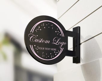 May include: Black circular sign with a white custom logo and the text "Your Text Here" in a pink circle with white dots. The sign is mounted on a black metal bracket.