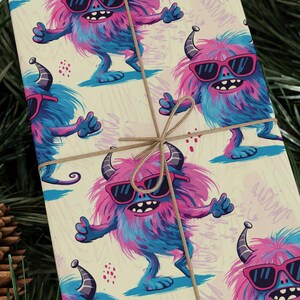 Puede incluir: Un papel de regalo con un patrón repetido de monstruos de dibujos animados azules y rosas que llevan gafas de sol. Los monstruos tienen el pelo esponjoso y sonríen. El fondo es de color beige claro.