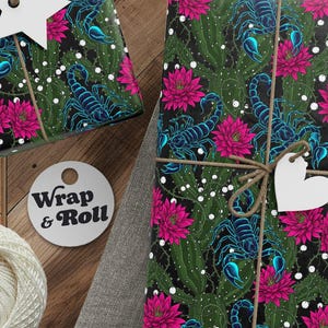 Puede incluir: Regalos envueltos con un patrón floral y escorpión verde oscuro. Los regalos están atados con hilo y adornados con etiquetas en forma de estrella y corazón. También se ven un carrete de hilo, tijeras y una etiqueta que dice "Wrap & Roll".