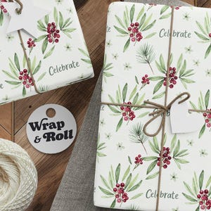 Puede incluir: Varios regalos envueltos con un estampado floral blanco con hojas verdes y bayas rojas. Cada regalo está atado con hilo y una etiqueta. También hay un carrete de hilo, tijeras y etiquetas. La palabra "Celebrate" está impresa en el papel de regalo.