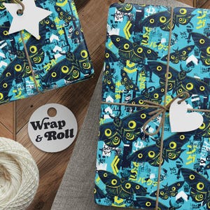 May include: Two rectangular gifts wrapped in bright blue paper featuring a repeating pattern of dark moths with yellow spots, geometric arrows, and Japanese text. Each package is tied with brown twine and includes a white star or heart tag.