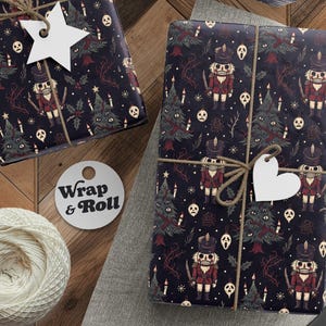 May include: Two rectangular packages wrapped in dark navy paper featuring a repeating pattern of nutcrackers, Christmas trees, and ghost-like masks. Each package is tied with brown twine and a white gift tag, one star-shaped and one heart-shaped.