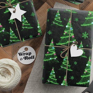 Puede incluir: Regalos envueltos con papel negro con árboles de Navidad verdes y copos de nieve. Los regalos están atados con hilo y adornados con etiquetas blancas en forma de estrella y corazón. También hay un carrete de hilo, tijeras y etiquetas.