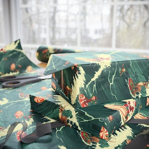May include: Wrapping paper featuring a dark green background with a repeating pattern of Santa Claus, elves, and reindeer surfing on waves, interspersed with red and white peppermint candies. The paper is shown covering two rectangular boxes.