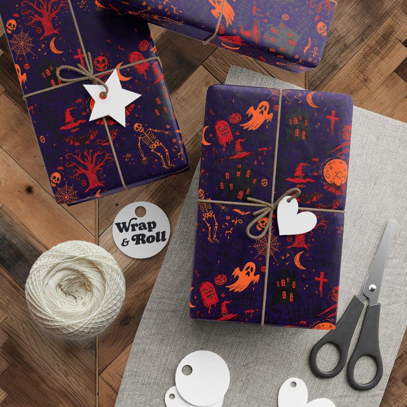 A gift wrapped in spooky Halloween wrapping paper. Features orange and red illustrations of skeletons, ghosts, haunted houses, and skulls on a dark purple background. The present is tied with twine and surrounded by festive pine branches.