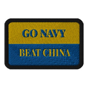 May include: Embroidered patch with a black border, featuring a yellow top section and a blue bottom section. The text "GO NAVY" is embroidered in blue on the yellow section, and "BEAT CHINA" is embroidered in blue on the blue section.