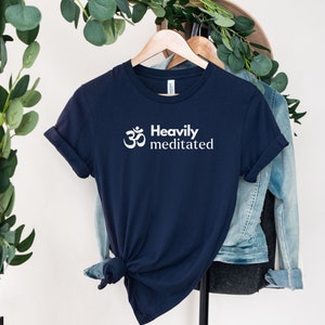 May include: A navy blue t-shirt with a white Om symbol and the text "Heavily Meditated" printed on the front.