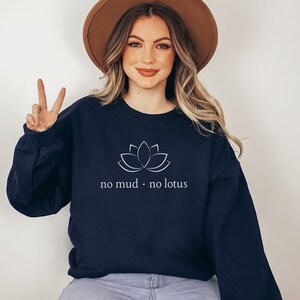 Op de afbeelding: Een donkerblauw sweatshirt met een witte lotusbloem afbeelding en de tekst "no mud. no lotus".