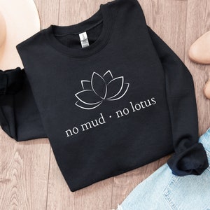 Op de afbeelding: Zwart sweatshirt met een witte lotusbloem afbeelding en de tekst "no mud. no lotus".